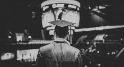 Graduate wearing cap and gown from behind in black and white