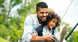 Smiling Black father and child on a swing