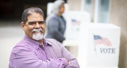Smiling Latino man in front of voting booths