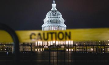 Blurry caution tape in foreground with U.S. Capitol building in background at night