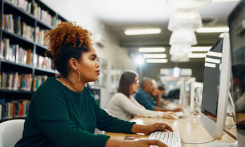 Black woman working at computer in college library