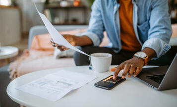 Person looking at bills on their living room couch