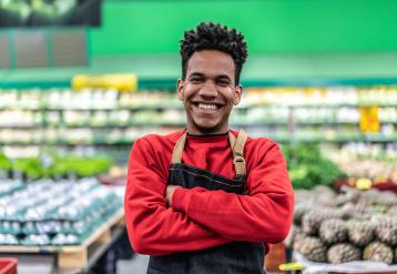 Smiling black retail worker in front of groceries