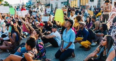 Black woman kneeling at a protest