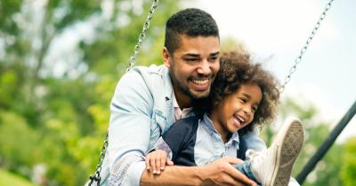 Smiling Black father and child on a swing