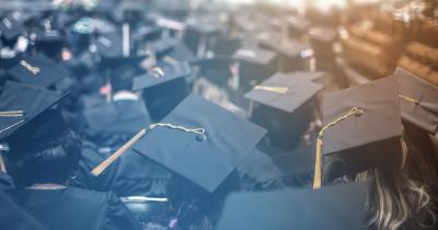 Cap and gowned students facing away at a graduation ceremony