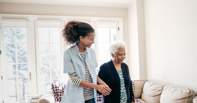 Home care aide helping an elderly black woman