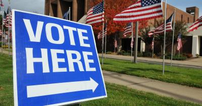 "Vote Here" sign in the grass in front of a polling station